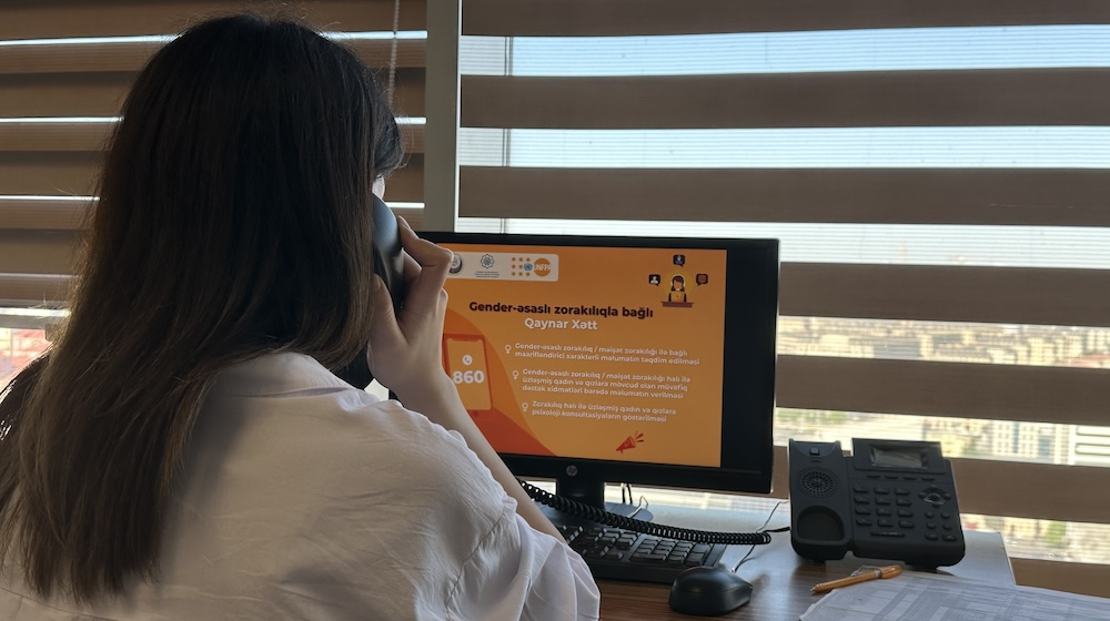 Une femme au téléphone regarde un écran d’ordinateur