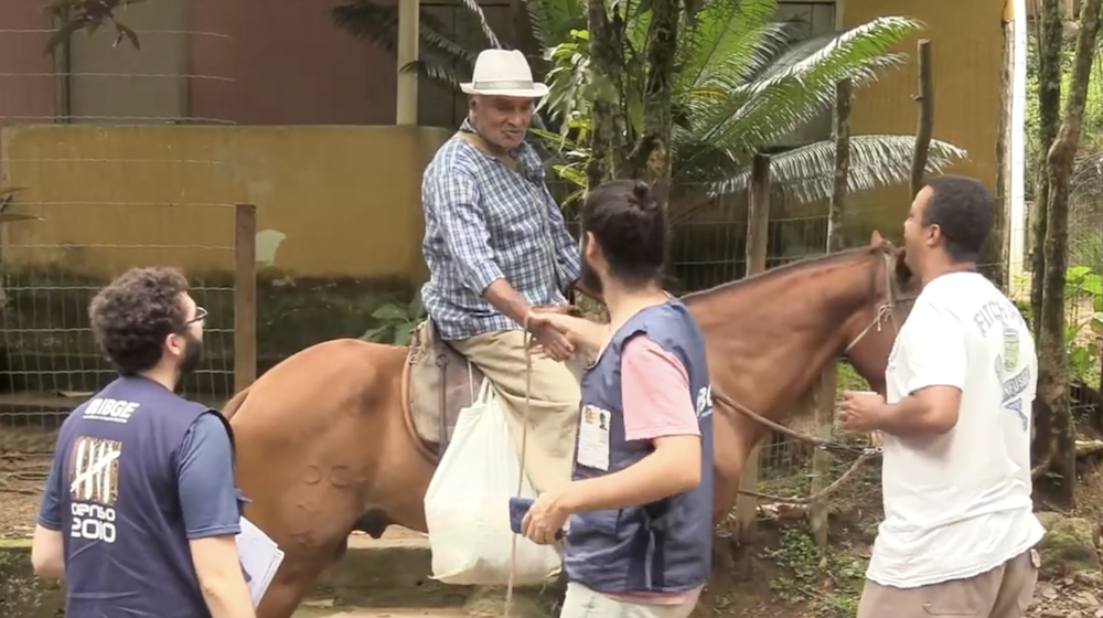 Un homme à cheval serre la main d’un autre homme, tandis que deux autres se tiennent à côté.