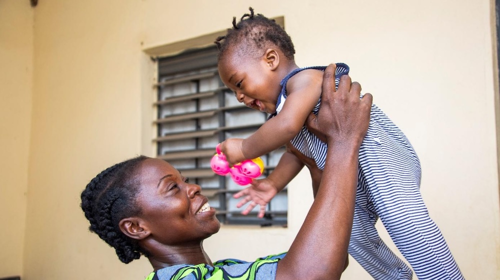 A woman holds a baby girl in the air