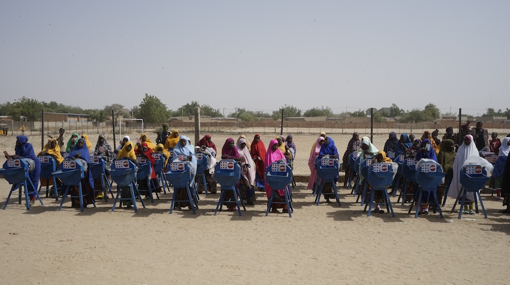 Des adolescentes se tiennent près de broyeurs à grain portant le logo de l’UNFPA