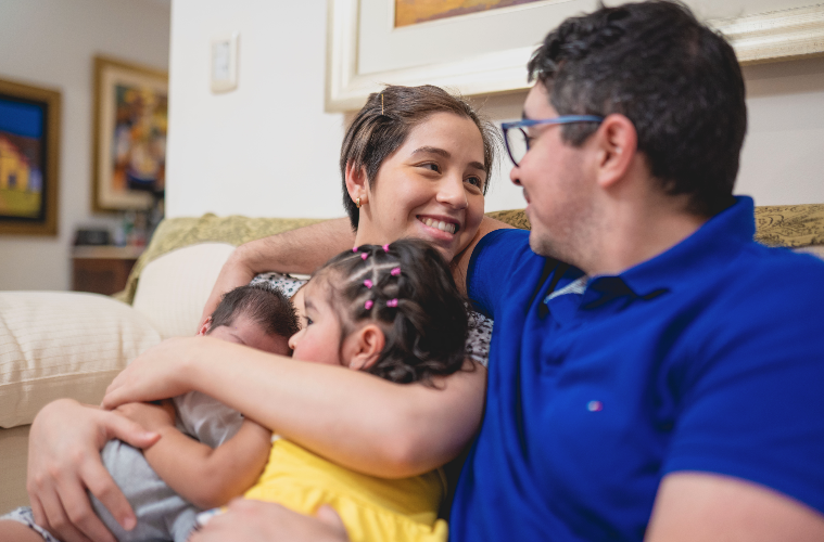 Une femme et un homme tiennent dans leurs bras deux enfants, et se regardent dans les yeux.