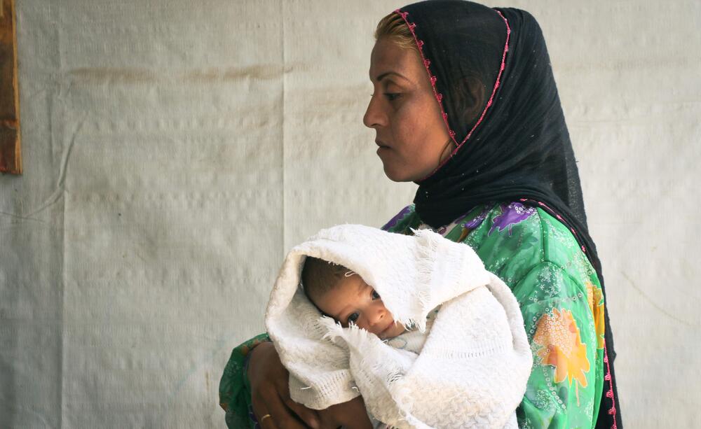 A woman carries her newborn child.