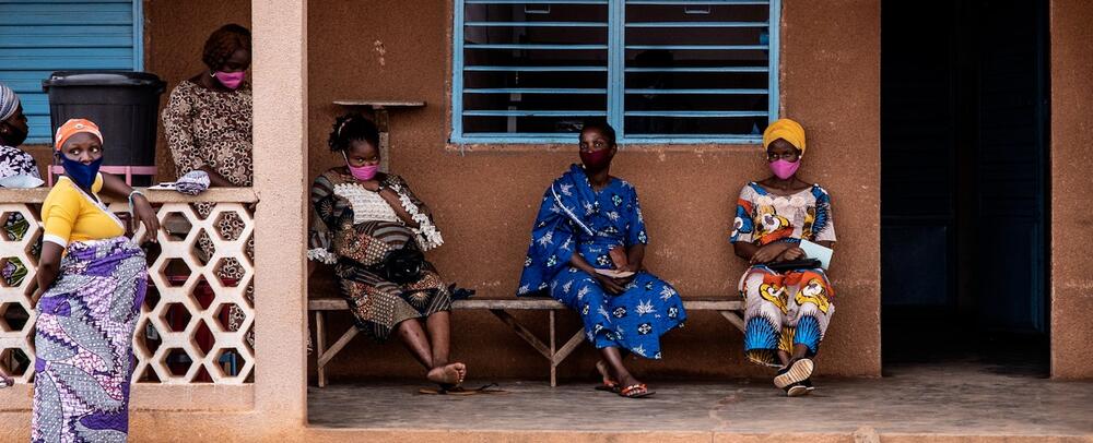 Women seated and standing outside of a building.