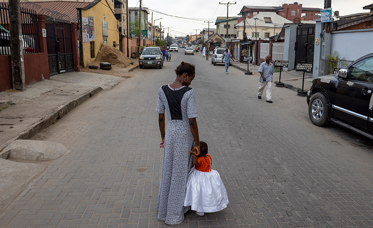 A mother holds the hand of her daughter in the middle of the road