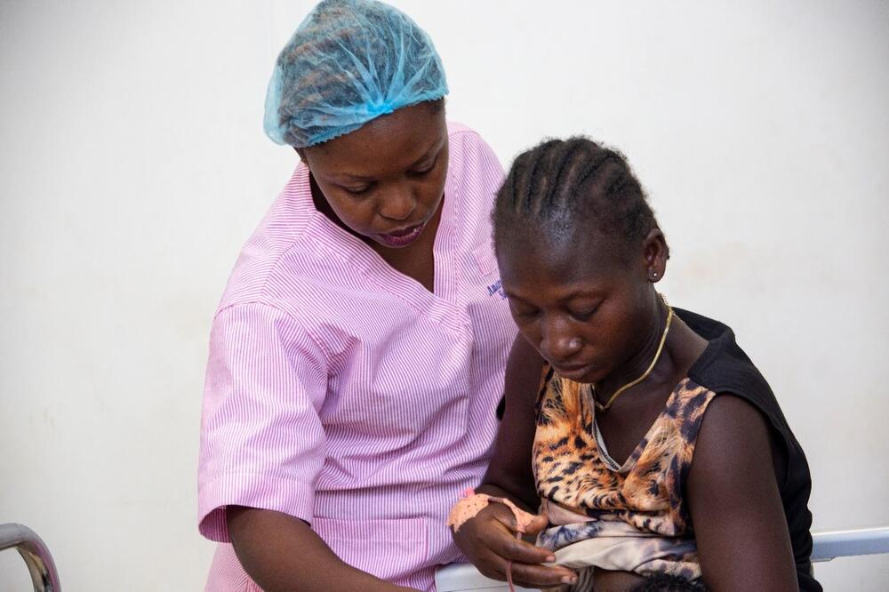 Une femme se penche vers une autre tenant un bébé.