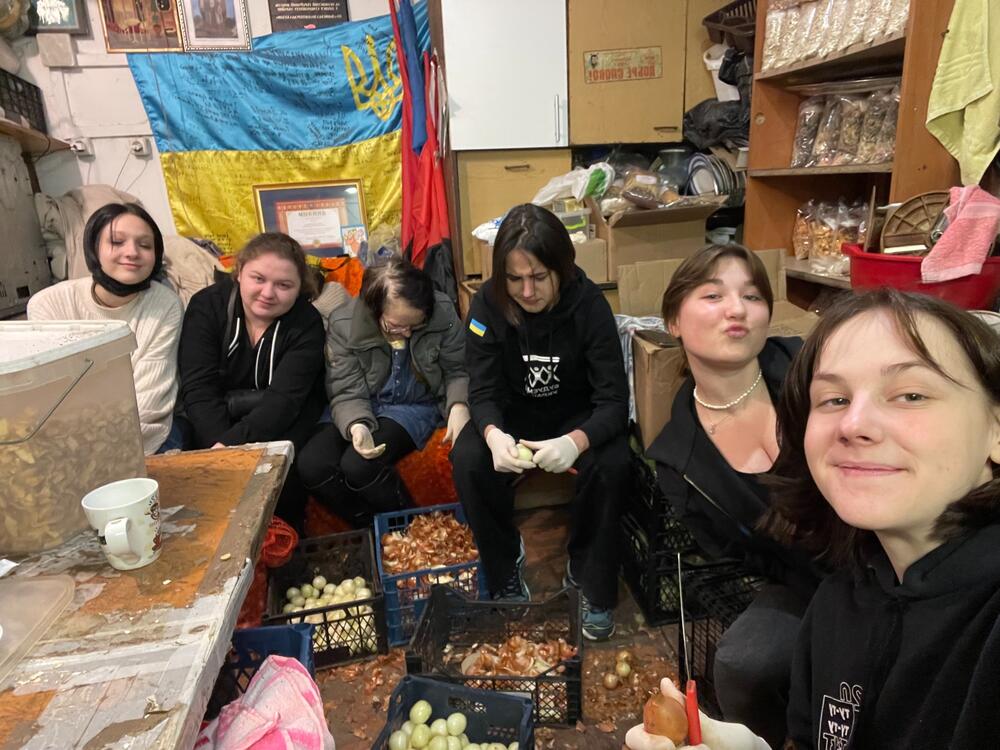 Mujeres pelando vegetales con otras voluntarias para preparar almuerzos para los militares. 