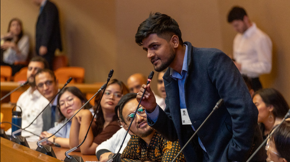 man speaking into microphone next to audience