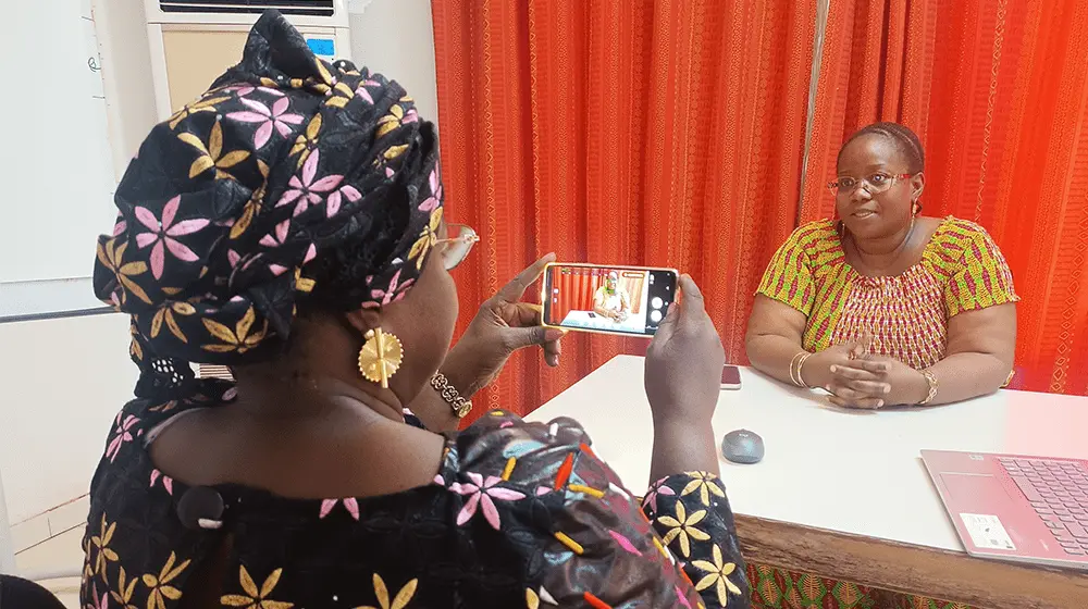 Une femme en filme une autre avec un téléphone portable.