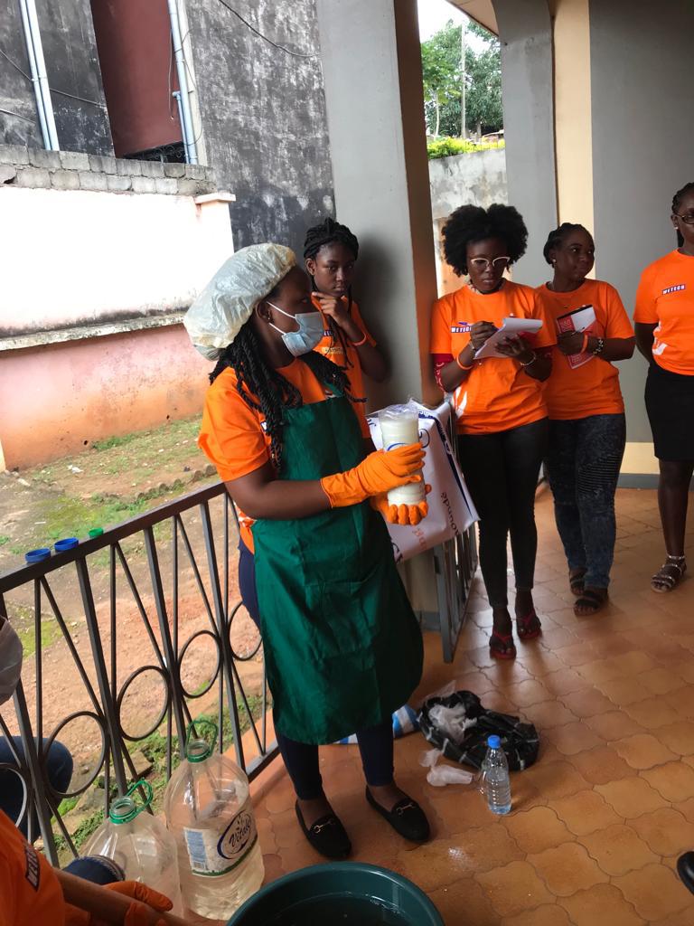 Five women watch a soap-making demonstration