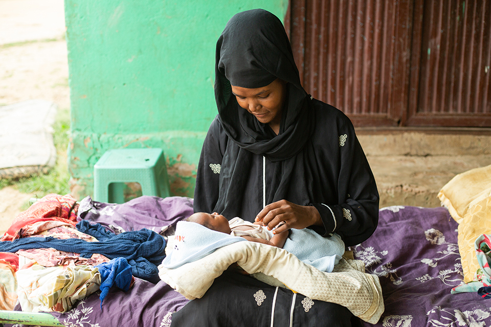 Une femme est assise, un bébé sur les genoux.