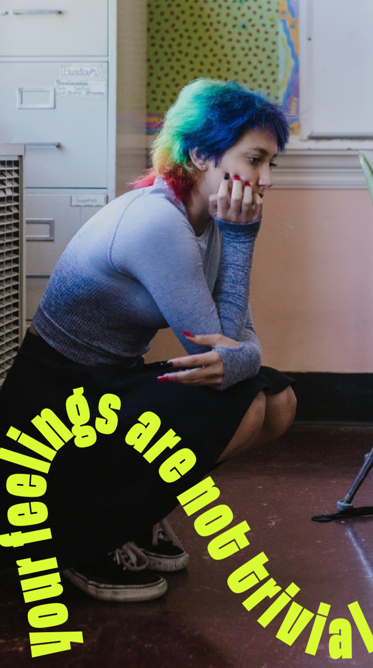 A woman sits on the floor alone.