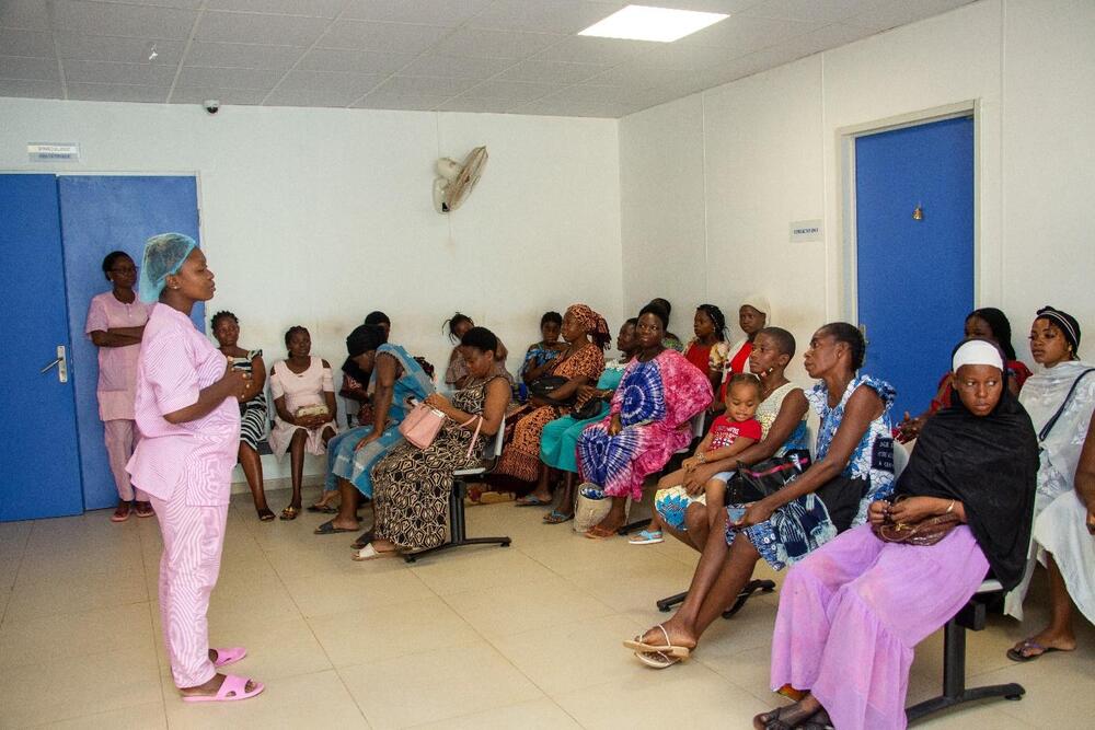  Une femme en blouse rose se tient debout devant un groupe de femmes enceintes.