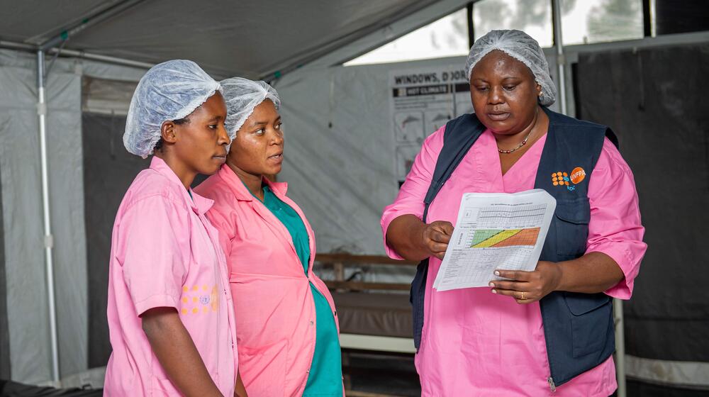 Trois sages-femmes examinent des dossiers médicaux.