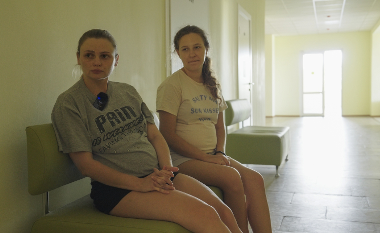  Two pregnant women sit on a bench in a hospital