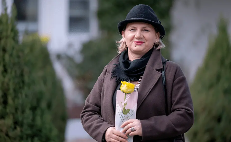 Une femme tient une rose jaune.