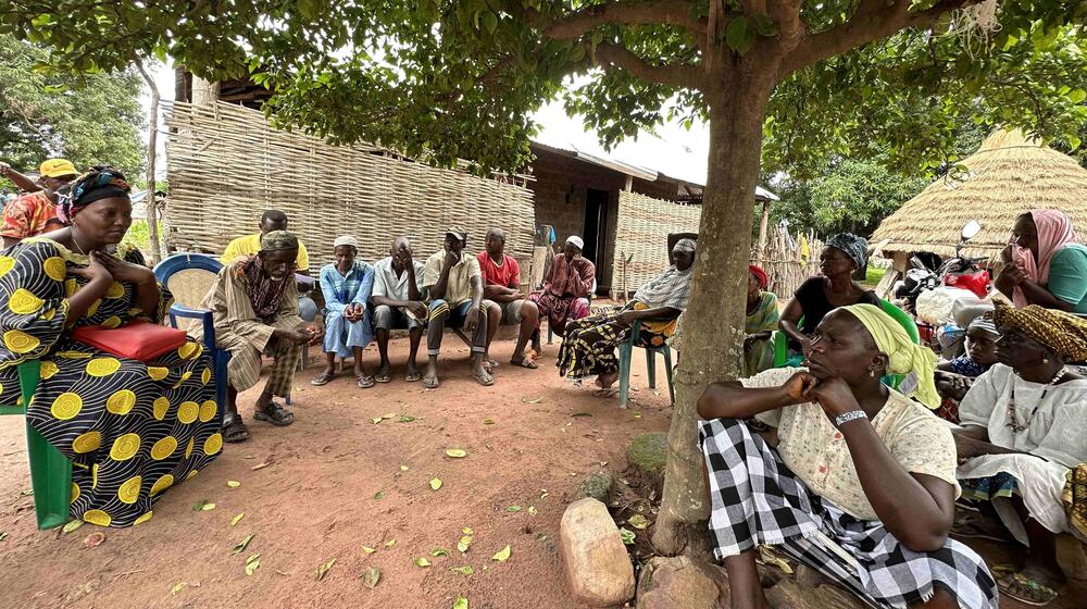 A group of people sit in a circle and listen to a speaker.