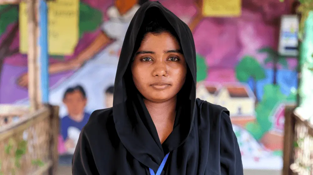 A portrait of a young woman wearing a head covering and black clothing.