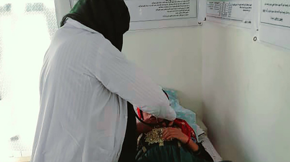 A medical worker assists a patient who is laying down.