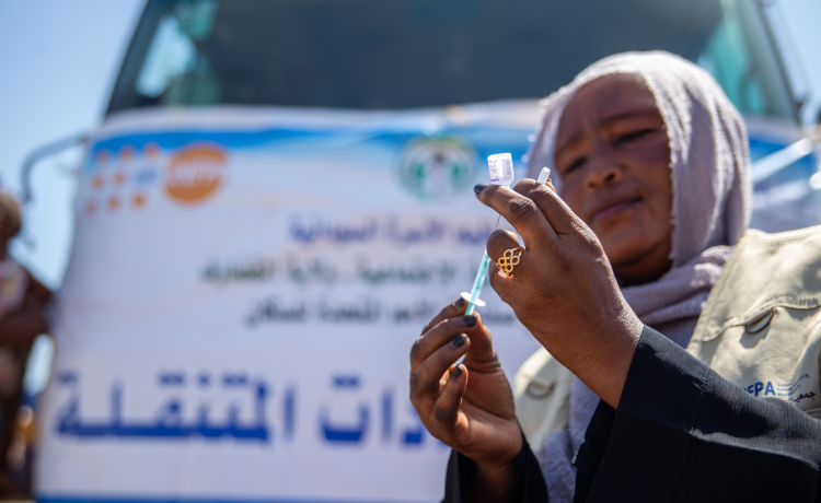 A female health worker inspects a syringe