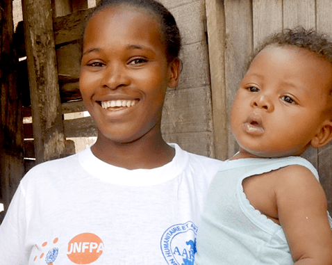 A young refugee woman holds her son.