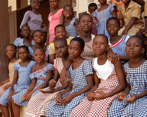 Girls sit outside their school.