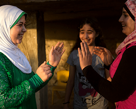 Adolescent girls play a clapping game.