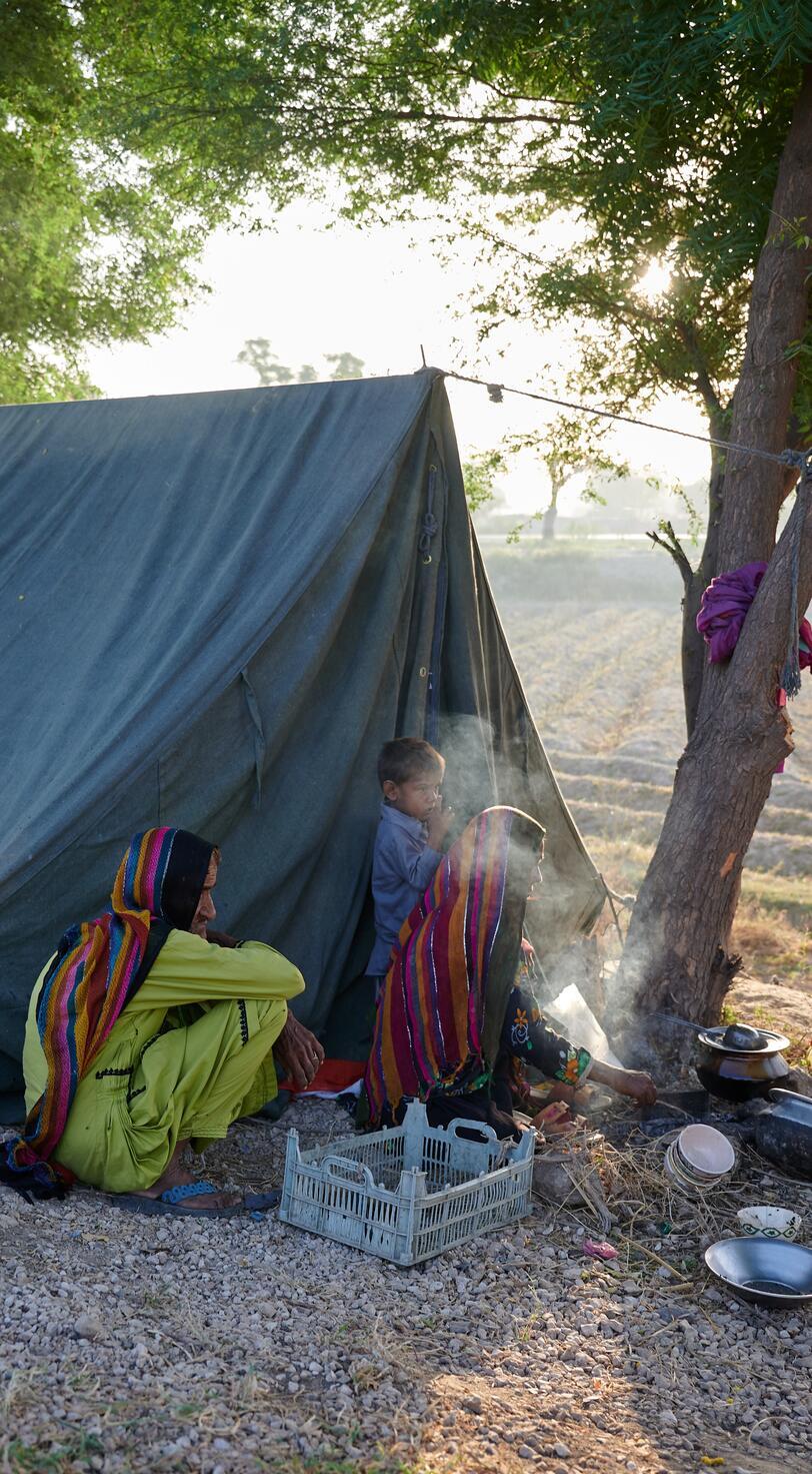 A family cooks by a tent.