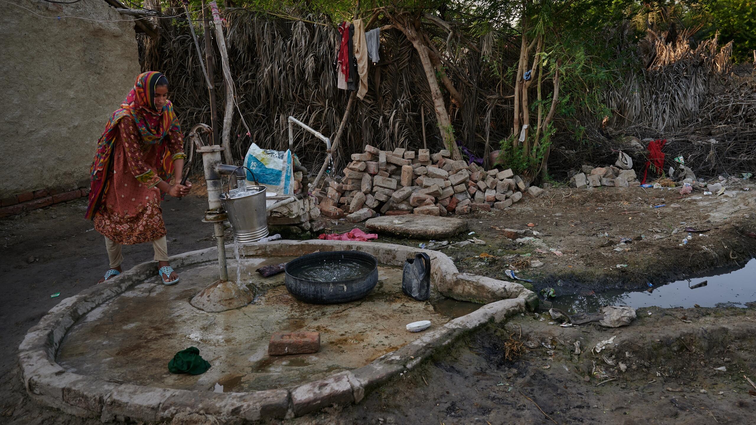 A woman pumps water from a well.