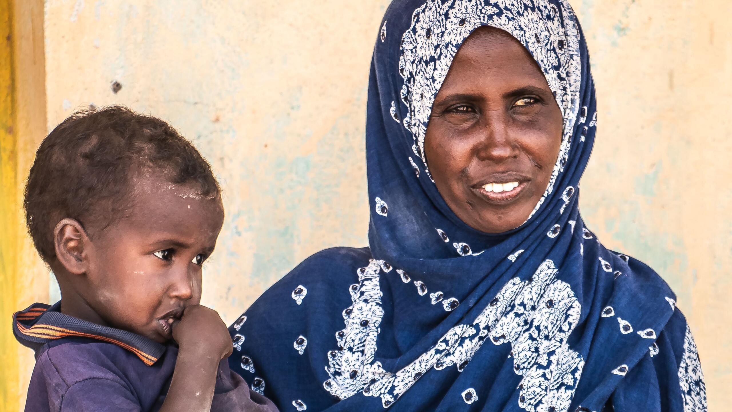 A woman carries a small child.