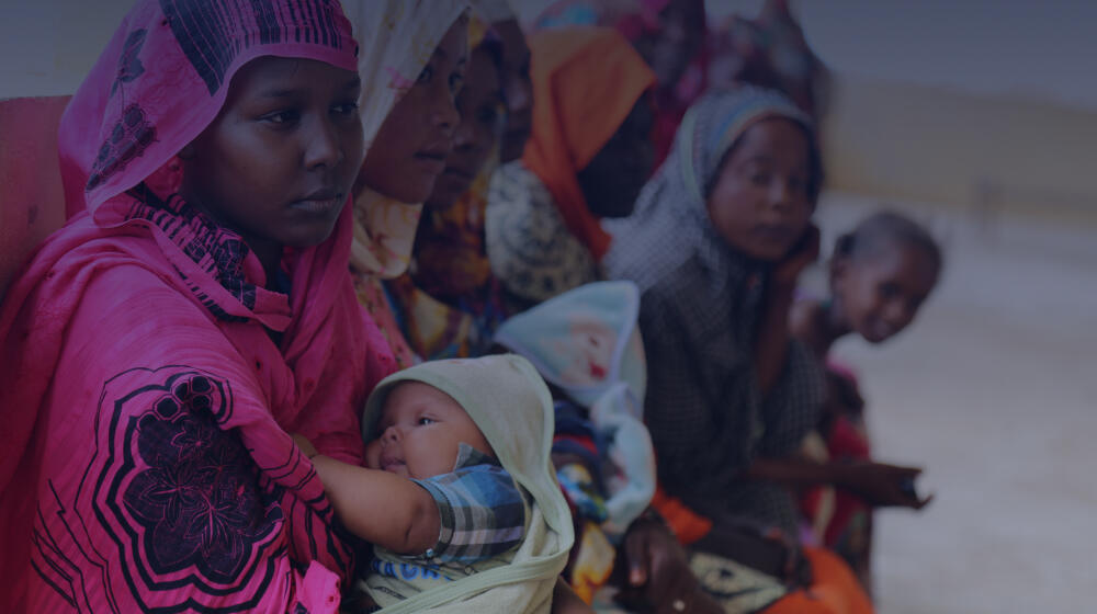 Young woman with pink headscarf holding baby