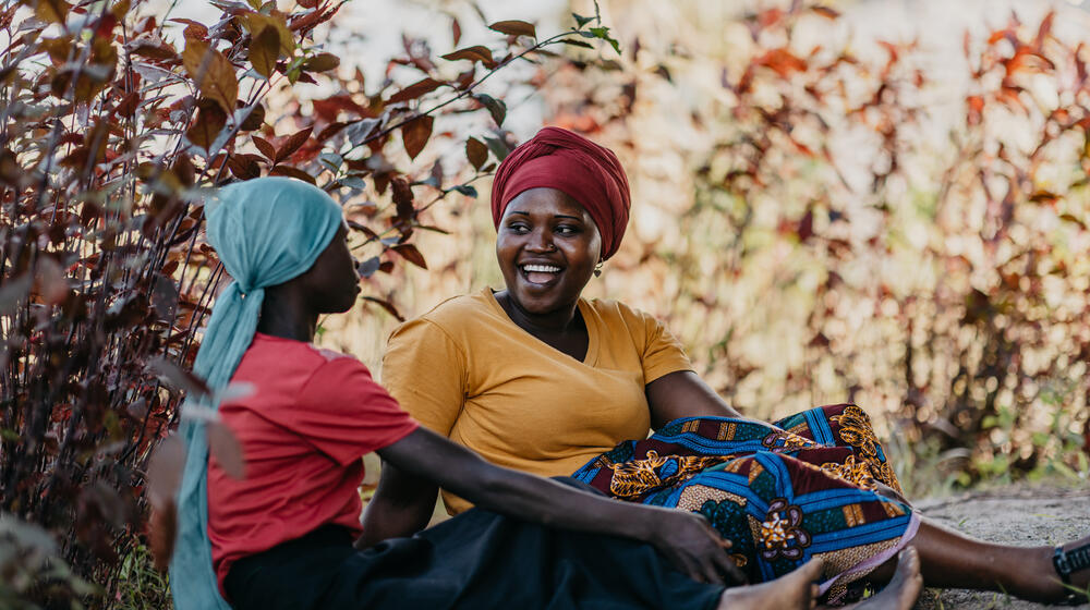 Two women sit together outdoors during a counseling session.