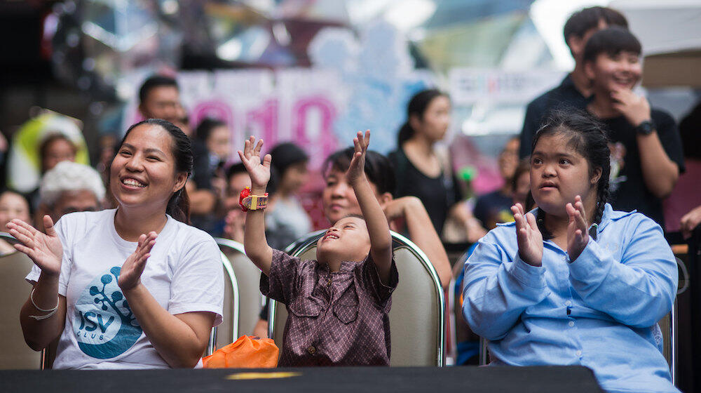 trois personnes sourient et applaudissent