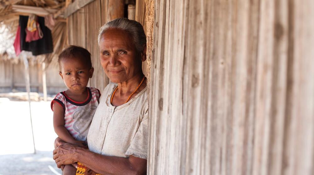 An elderly woman holds a child.