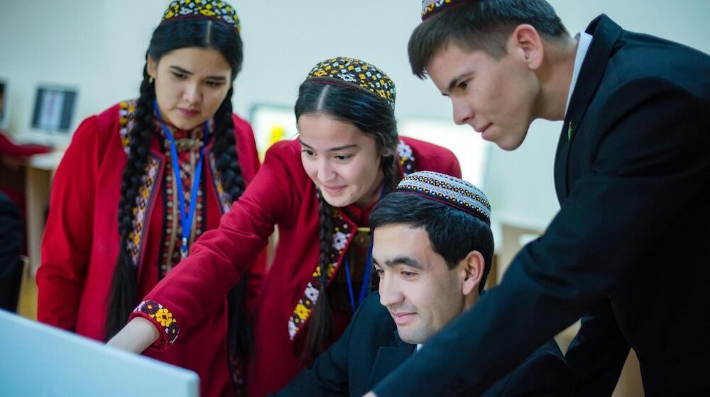 Cuatro jóvenes reunidos en torno a una computadora.