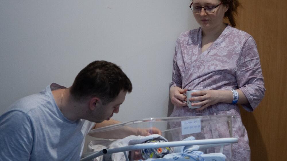 Un homme et une femme regardent un nouveau-né dans une couveuse