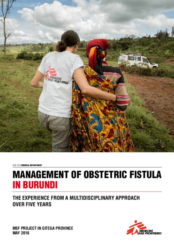 MSF worker walks together with a woman in red in a green field