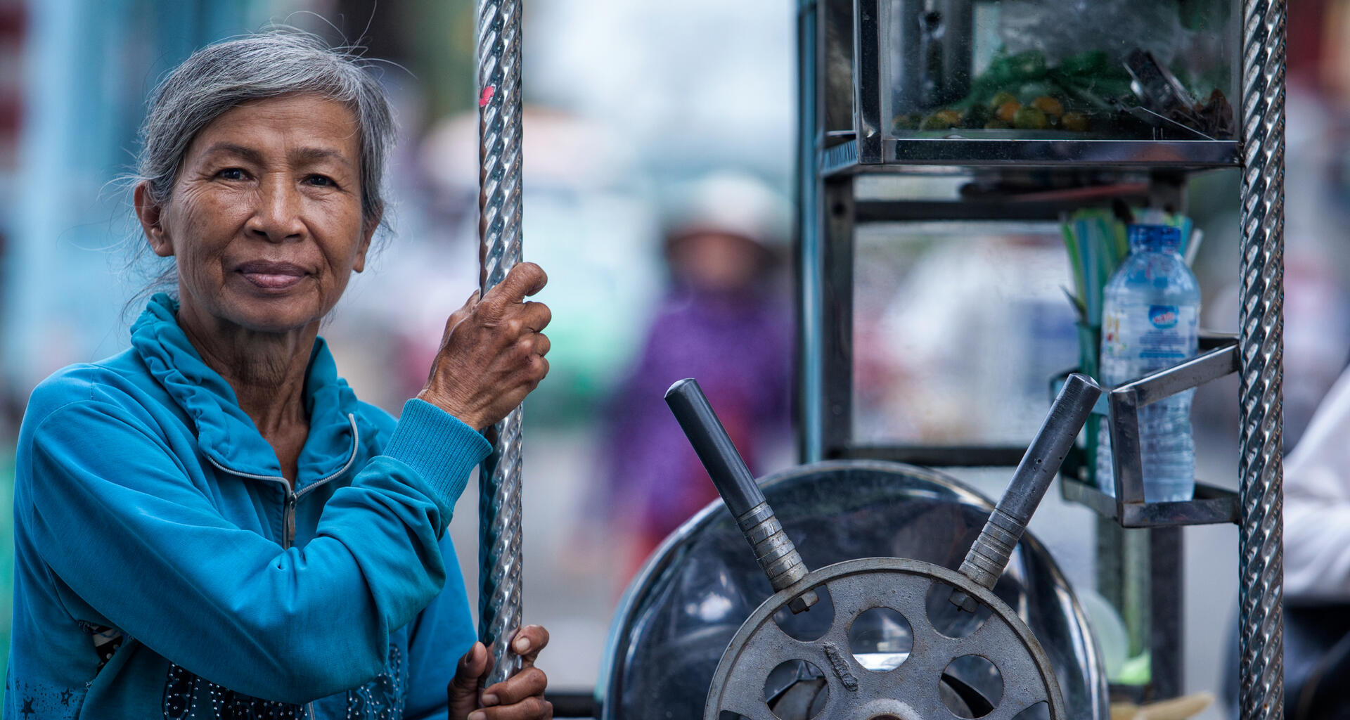 An older woman poses with machinery.