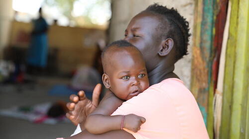 A woman holds a young child in her arms.