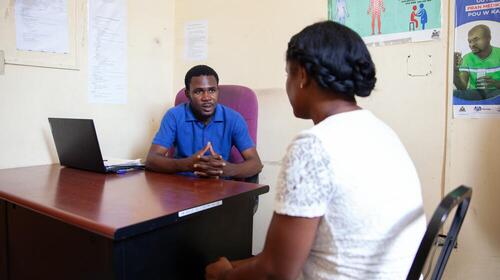 Un homme parle à une femme derrière un bureau