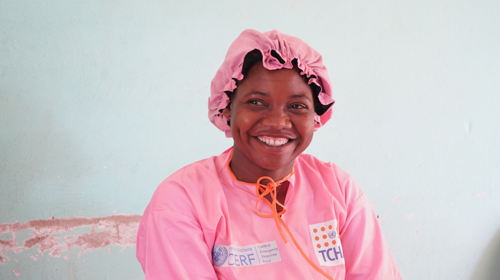  A woman wearing pink medical scrubs smiles.